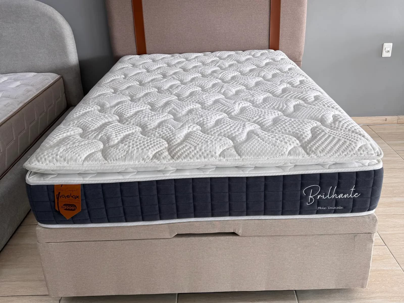 Colchão Prorelax Brilhante com pillow top sobre box baú bege com cabeceira no showroom da Decorelar Colchões, em Inoã, Maricá