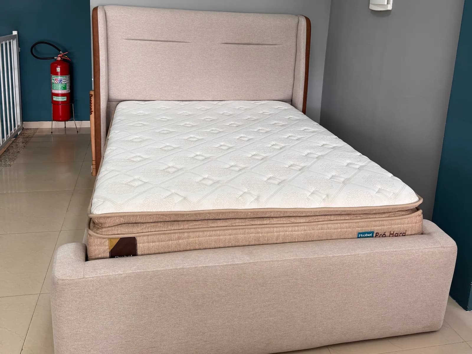 Colchão Probel Pró Hard com pillow top montado em cama estofada bege no showroom da Decorelar Colchões, em Inoã, Maricá