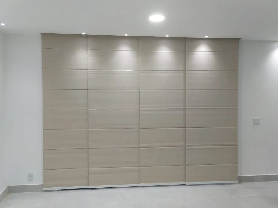 Persiana painel com quatro painéis de tecido bege cobrindo a parede da sala