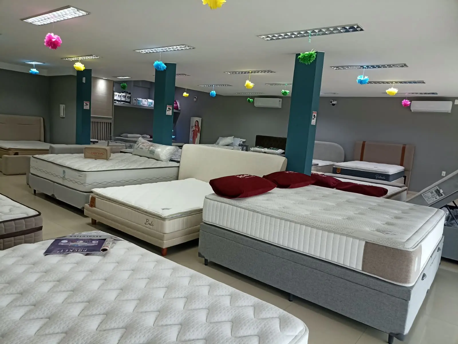 Salão da Decorelar Colchões em Inoã, Maricá, com camas box, box baú e cabeceiras montadas para testar
